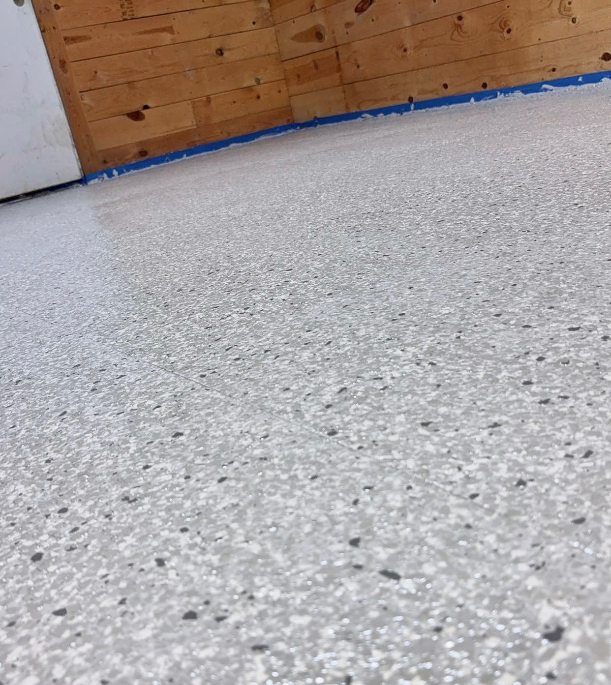 Glossy garage floor finished with gray and black decorative epoxy flake